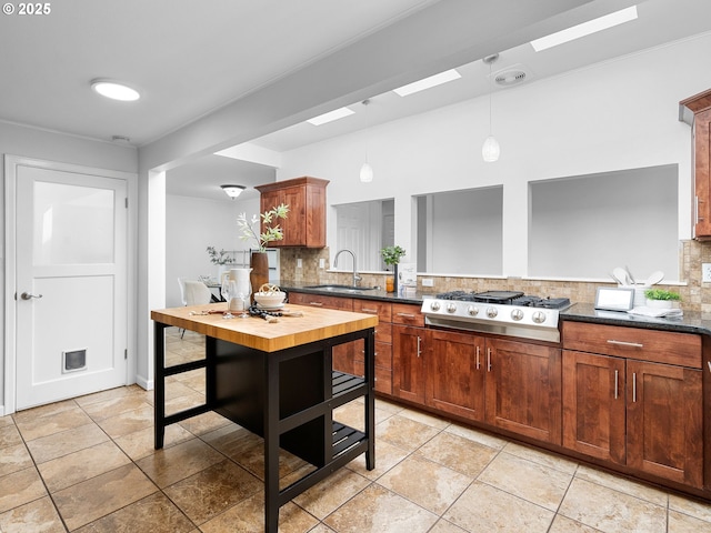 8920 SW 9th Dr, Portland, OR 97219 - kitchen featuring a sink, backsplash, stainless steel gas cooktop, pendant lighting, and dark countertops