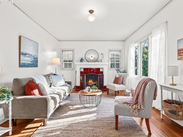 living room with a tiled fireplace, hardwood / wood-style flooring, and ornamental molding