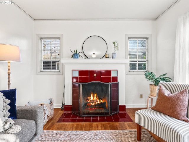 sitting room featuring a tiled fireplace, ornamental molding, and dark hardwood / wood-style flooring