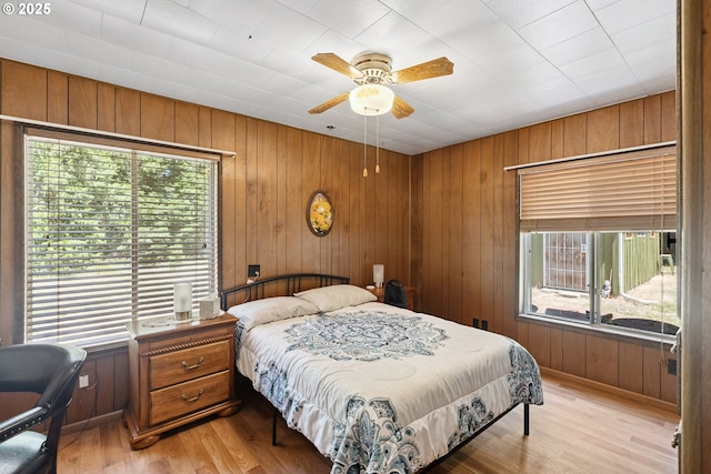 7291 Rice Valley Rd, Oakland, OR 97462 - bedroom featuring multiple windows, light wood-style flooring, wood walls, and a ceiling fan