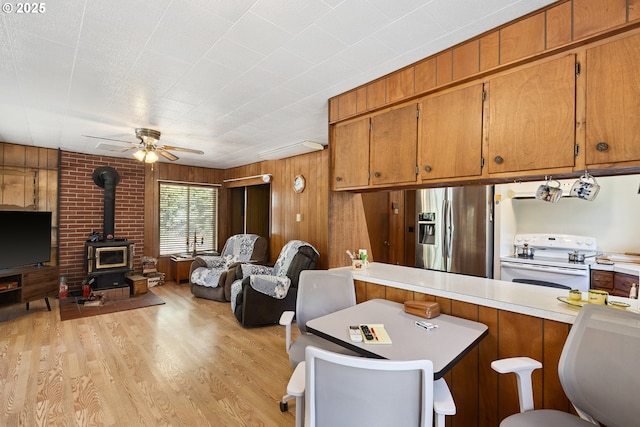 7291 Rice Valley Rd, Oakland, OR 97462 - kitchen with stainless steel fridge with ice dispenser, white electric stove, open floor plan, a wood stove, and brown cabinets