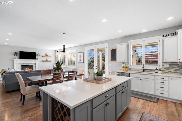 kitchen with sink, white cabinetry, decorative light fixtures, a kitchen island, and decorative backsplash