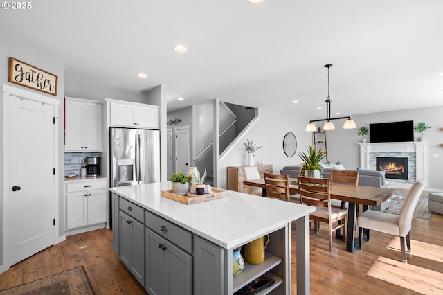 kitchen featuring white cabinetry, decorative light fixtures, stainless steel fridge, gray cabinets, and backsplash