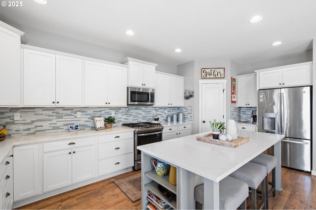 kitchen with white cabinetry, stainless steel appliances, a center island, and decorative backsplash