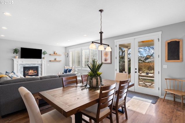 dining space featuring french doors, a stone fireplace, and hardwood / wood-style floors