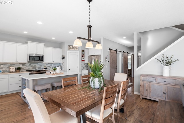 dining area featuring a barn door and dark hardwood / wood-style floors