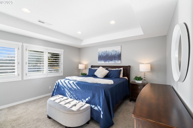 bedroom with carpet floors and a raised ceiling