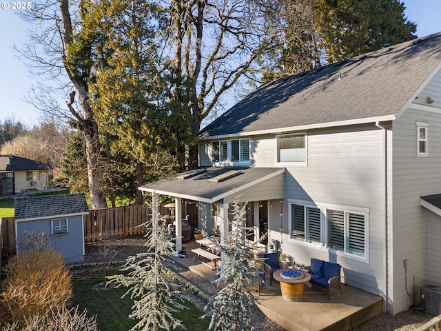 back of house with a storage shed, an outdoor living space with a fire pit, and a patio