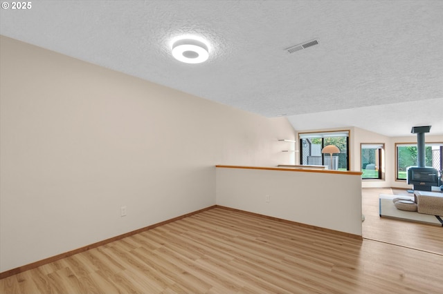 13802 NW 10th Ct, Vancouver, WA 98685 - interior space with baseboards, vaulted ceiling, light wood-style flooring, a textured ceiling, and a wood stove