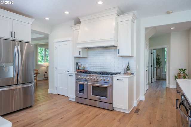 8751 SW 194th Pl, Beaverton, OR 97007 - kitchen with stainless steel appliances, custom range hood, light wood finished floors, white cabinets, and backsplash