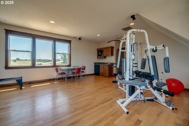 exercise area with light wood finished floors, baseboards, and recessed lighting