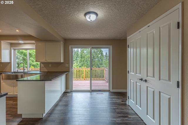 3026 NW Norwood St, Camas, WA 98607 - kitchen with a sink, a peninsula, dark wood-style floors, white cabinets, and baseboards
