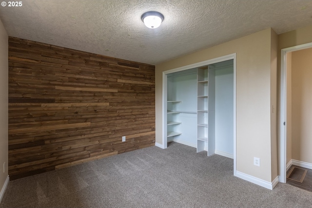 3026 NW Norwood St, Camas, WA 98607 - unfurnished bedroom with wooden walls, a textured ceiling, dark carpet, a closet, and baseboards
