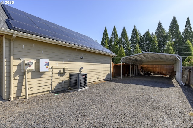 50 W Taylor St, Carlton, OR 97111 - view of property exterior featuring a carport, central AC, roof mounted solar panels, gravel driveway, and fence