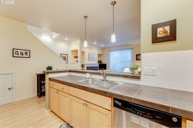 kitchen featuring pendant lighting, sink, stainless steel dishwasher, light brown cabinets, and light hardwood / wood-style flooring