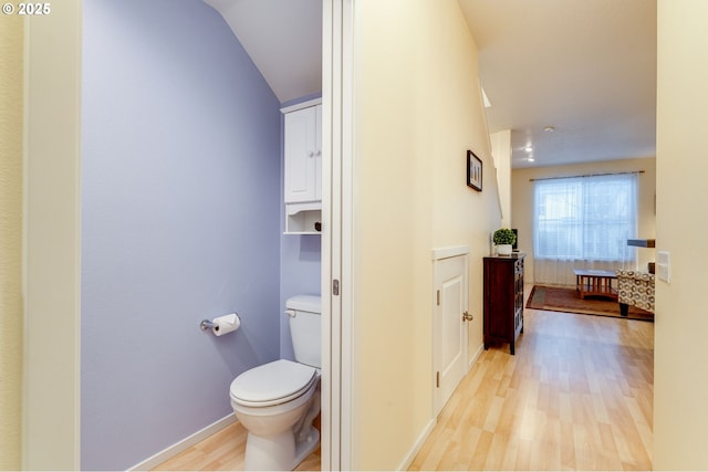 bathroom featuring wood-type flooring, vaulted ceiling, and toilet