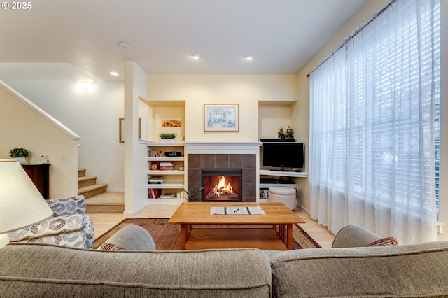 living room with a tile fireplace and light hardwood / wood-style floors