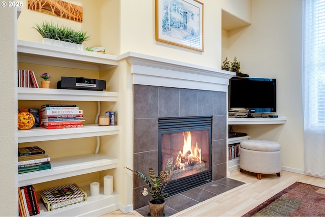 interior details featuring built in features, wood-type flooring, and a tile fireplace