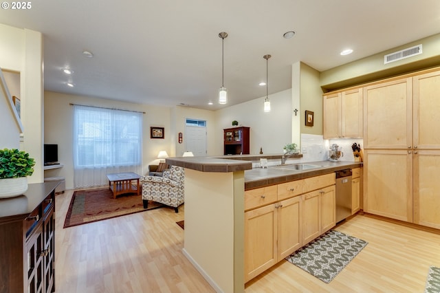 kitchen with sink, stainless steel dishwasher, light brown cabinetry, and kitchen peninsula