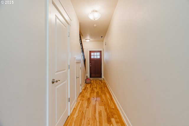 hall featuring light wood-style flooring and baseboards