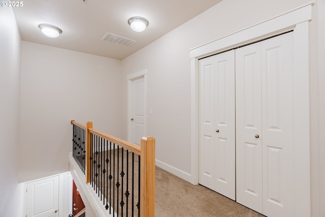 corridor featuring baseboards, light carpet, visible vents, and an upstairs landing