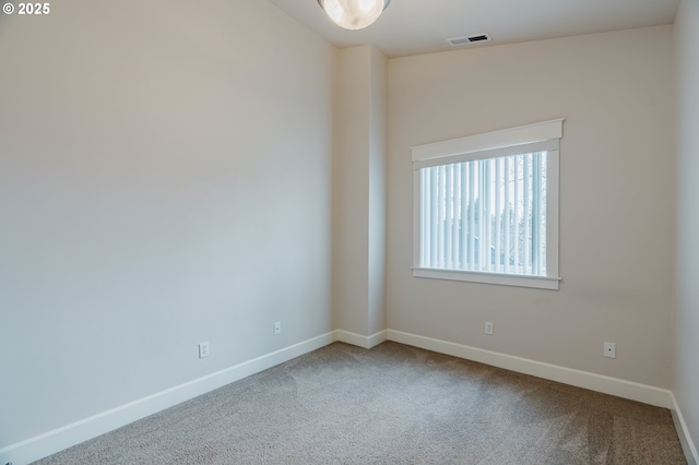 unfurnished room with carpet, visible vents, and baseboards