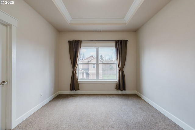 carpeted empty room featuring baseboards, a tray ceiling, visible vents, and crown molding