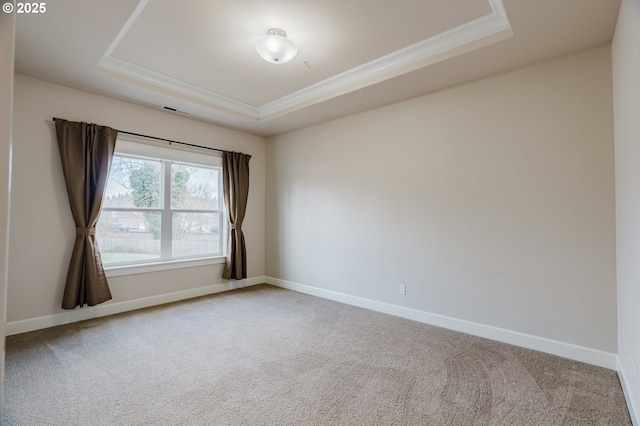 carpeted spare room featuring baseboards, a tray ceiling, and crown molding