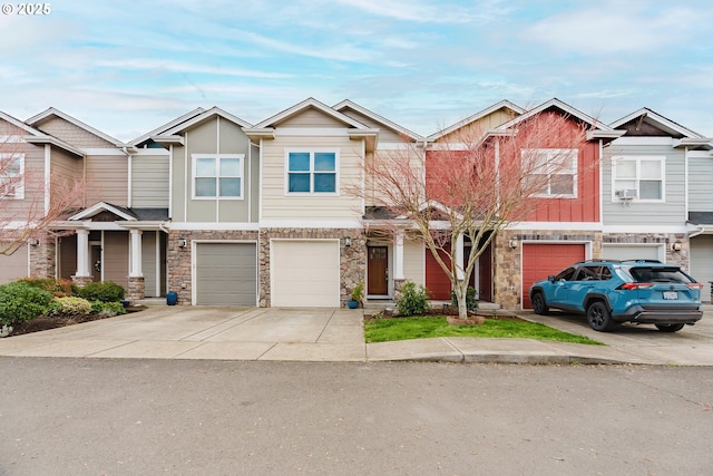 townhome / multi-family property with a garage, stone siding, and driveway