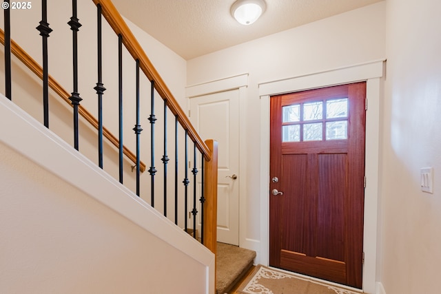 entryway featuring a textured ceiling and stairway