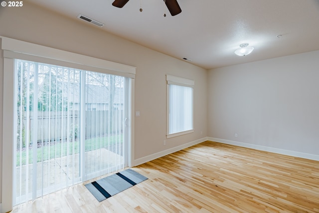 spare room featuring baseboards, visible vents, and wood finished floors