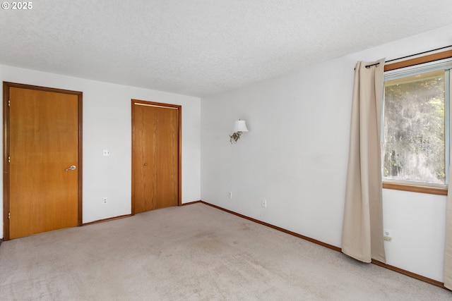 unfurnished bedroom featuring a textured ceiling, multiple windows, carpet flooring, a closet, and baseboards