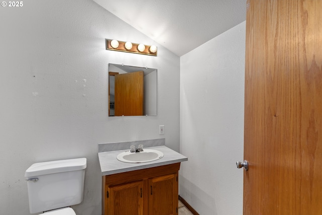 half bath featuring vaulted ceiling, vanity, and toilet