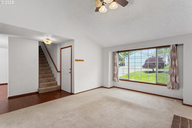 unfurnished living room with carpet, a textured ceiling, stairway, lofted ceiling, and baseboards