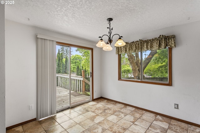unfurnished room featuring baseboards, a chandelier, and a textured ceiling