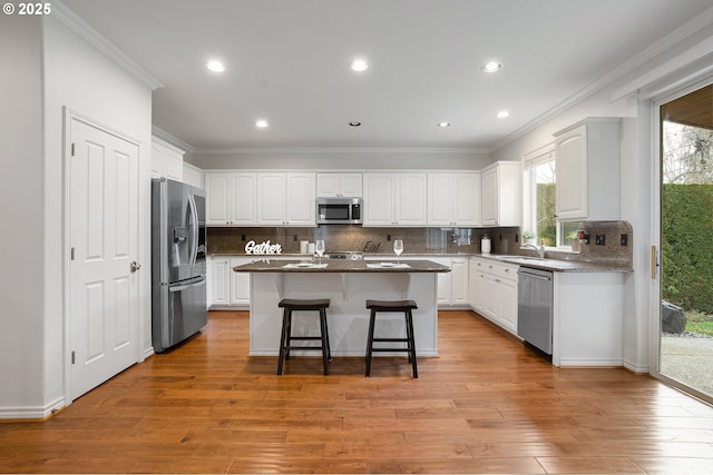 kitchen with stainless steel appliances, white cabinetry, a breakfast bar, and a center island