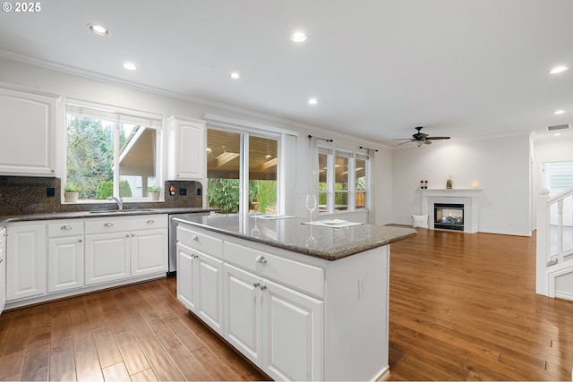 kitchen featuring white cabinets, ornamental molding, a multi sided fireplace, and a kitchen island