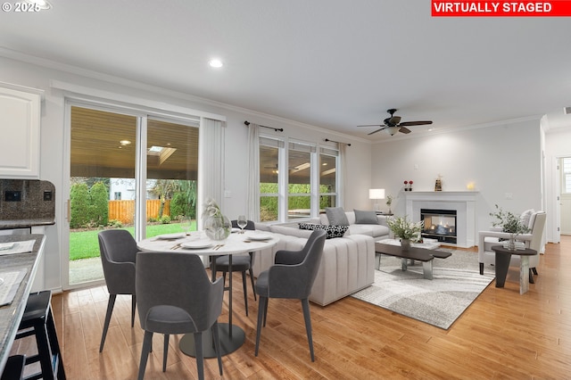 living room with light wood-type flooring, ceiling fan, and crown molding