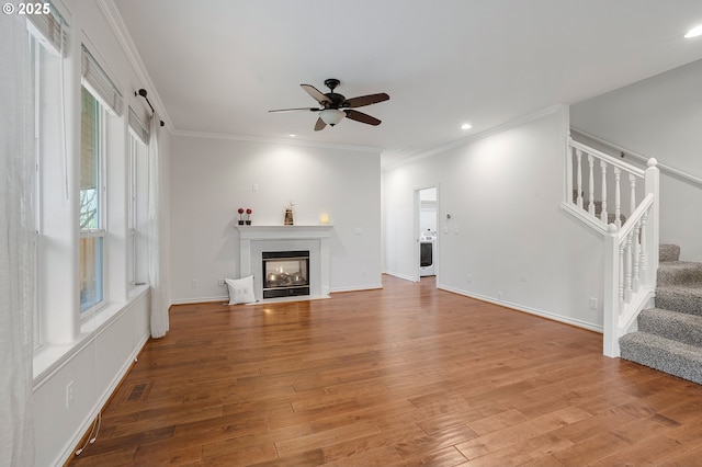 unfurnished living room with ceiling fan, washer / dryer, crown molding, and hardwood / wood-style flooring