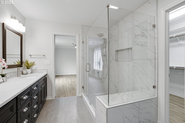 bathroom with a shower with door, vanity, and ceiling fan