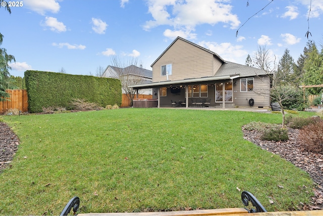 rear view of property with a patio area, a hot tub, and a yard