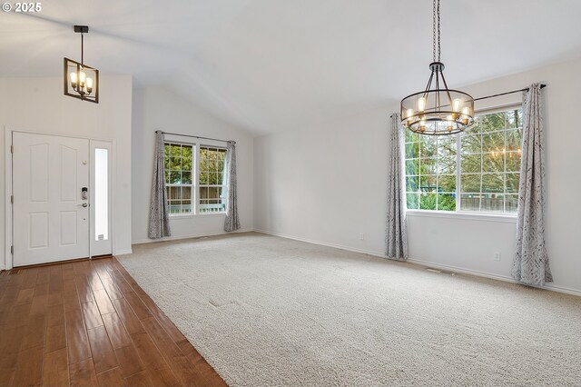 foyer with lofted ceiling, hardwood / wood-style floors, a healthy amount of sunlight, and a notable chandelier