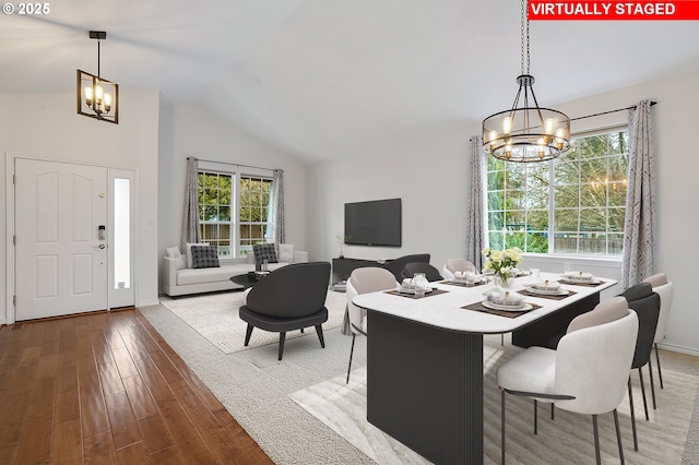 dining area featuring lofted ceiling, hardwood / wood-style flooring, a notable chandelier, and plenty of natural light