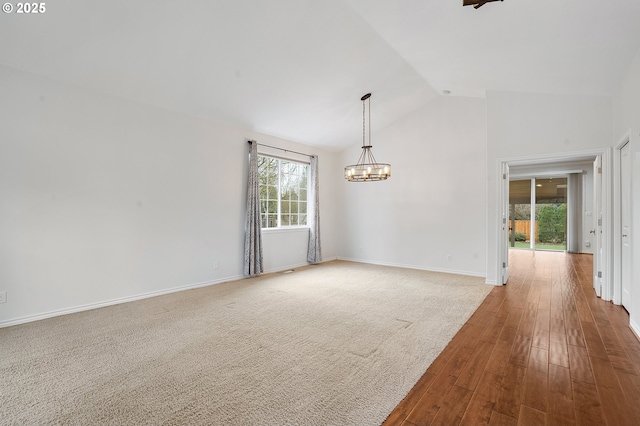 spare room with lofted ceiling, a chandelier, and hardwood / wood-style floors