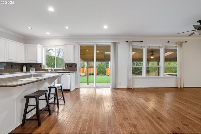 kitchen with white cabinets, ornamental molding, and a healthy amount of sunlight