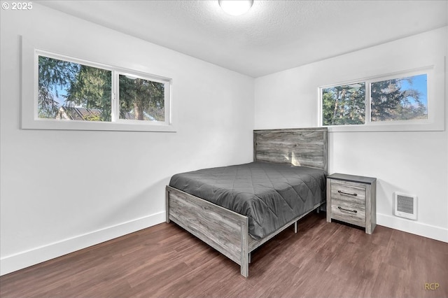 bedroom featuring dark hardwood / wood-style flooring and a textured ceiling