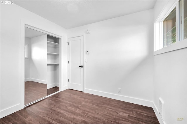 unfurnished bedroom featuring a closet and dark wood-type flooring