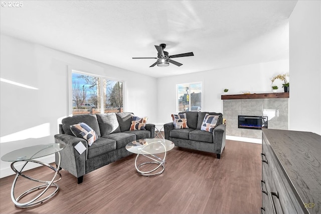 living room with ceiling fan, dark hardwood / wood-style flooring, and a tiled fireplace