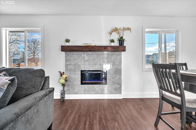 living room with dark wood-type flooring and a tiled fireplace