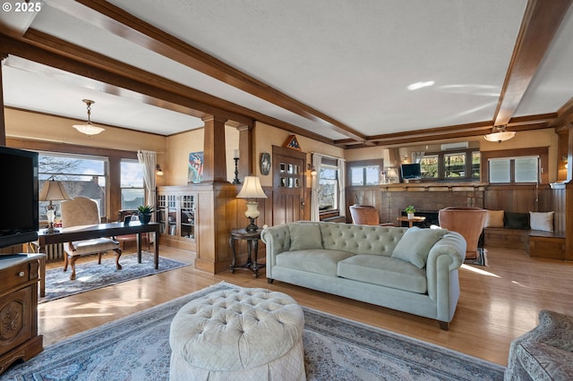 living room featuring a healthy amount of sunlight, a fireplace, beam ceiling, and wood finished floors